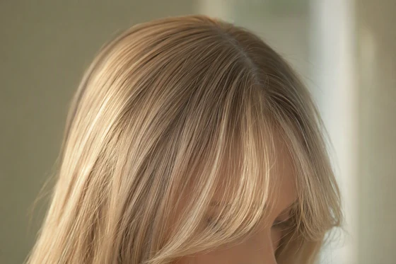 Wispy curtain bangs on fine blonde hair showing airy skin show-through from a shallow fringe section